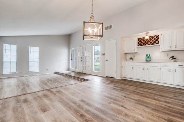 entryway with a chandelier, light hardwood / wood-style floors, and high vaulted ceiling