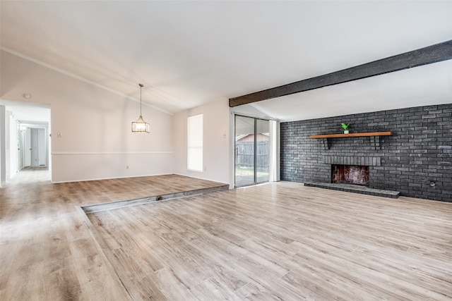 unfurnished living room with vaulted ceiling with beams, a fireplace, brick wall, and light wood-type flooring