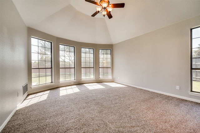 carpeted empty room featuring plenty of natural light, ceiling fan, and vaulted ceiling