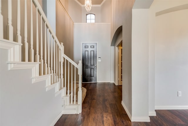 foyer entrance with dark hardwood / wood-style flooring, a towering ceiling, and ornamental molding