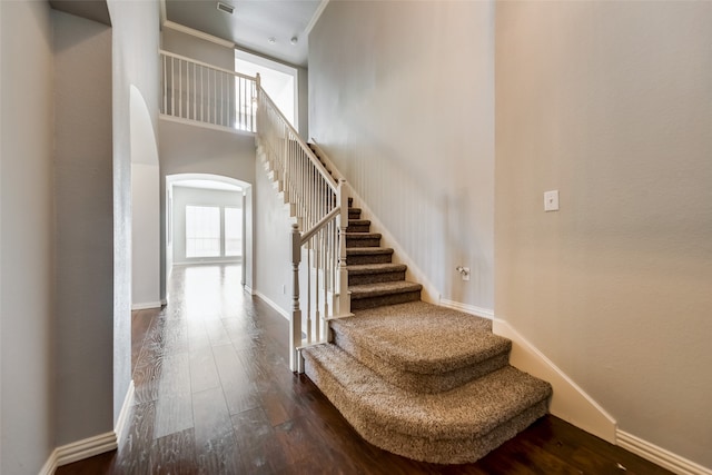 stairs with hardwood / wood-style flooring and a towering ceiling