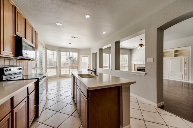 kitchen with sink, hanging light fixtures, backsplash, an island with sink, and appliances with stainless steel finishes