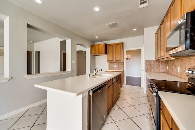 kitchen with light tile patterned flooring, stainless steel appliances, a kitchen island with sink, and sink