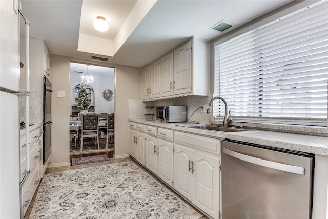 kitchen with backsplash, sink, white cabinets, and stainless steel appliances