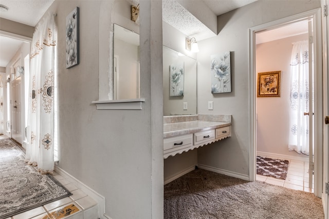 bathroom with vanity, a textured ceiling, and tile patterned flooring