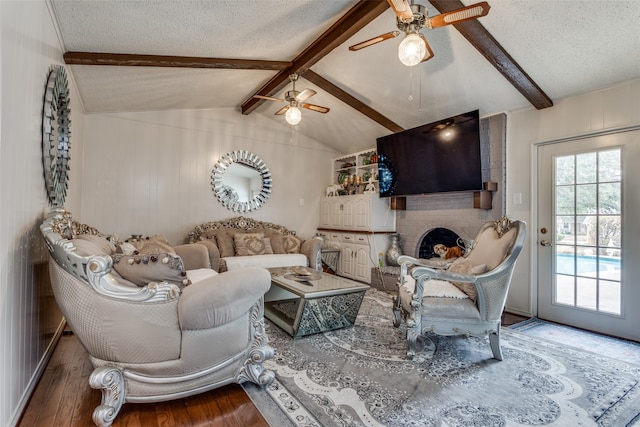 living room featuring lofted ceiling with beams, a fireplace, wood-type flooring, and a textured ceiling