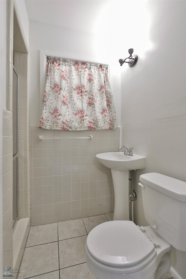 bathroom with tile patterned flooring, a shower, toilet, and tile walls