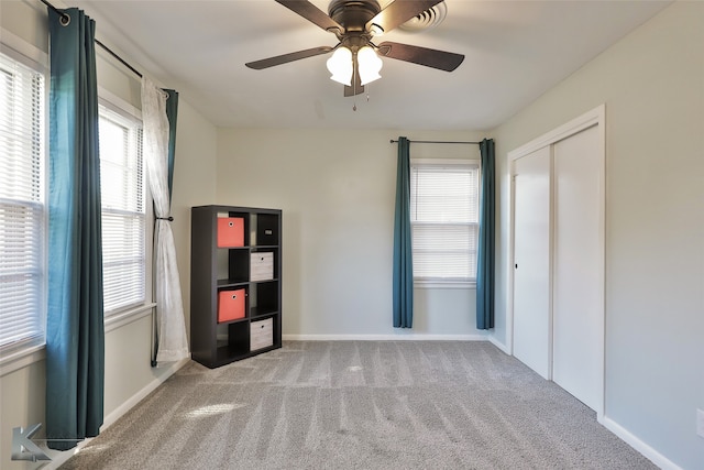 interior space with a closet, light colored carpet, and ceiling fan