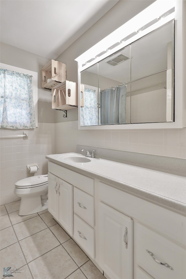 bathroom featuring tile patterned flooring, vanity, toilet, and tile walls