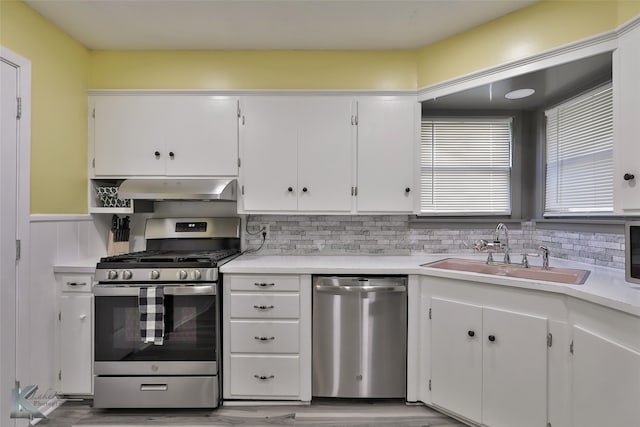 kitchen with white cabinets, sink, light wood-type flooring, appliances with stainless steel finishes, and extractor fan