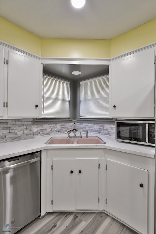 kitchen with decorative backsplash, stainless steel appliances, sink, light hardwood / wood-style flooring, and white cabinetry