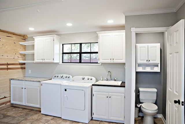 clothes washing area featuring crown molding, washer and clothes dryer, wood walls, and sink