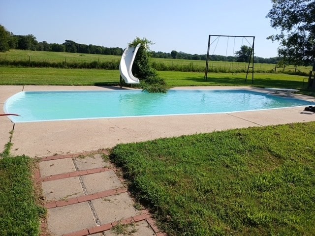 view of swimming pool featuring a diving board, a yard, and a water slide