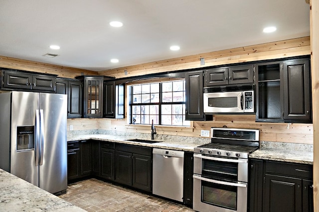 kitchen featuring light stone counters, sink, stainless steel appliances, and tasteful backsplash