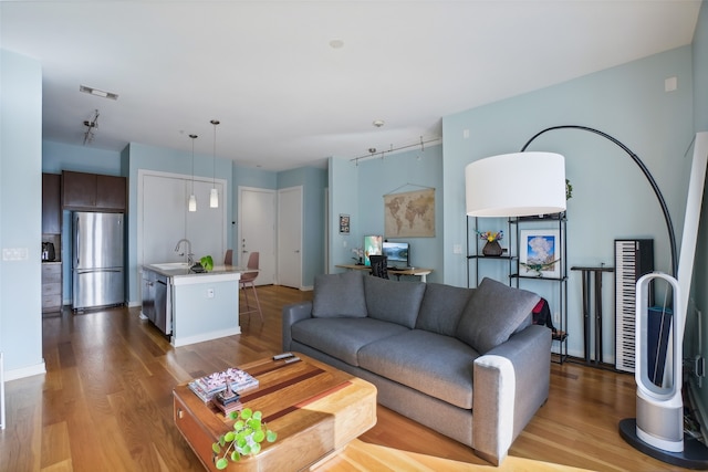 living room with rail lighting, light hardwood / wood-style floors, and sink