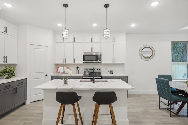 kitchen with a kitchen island with sink, sink, and appliances with stainless steel finishes