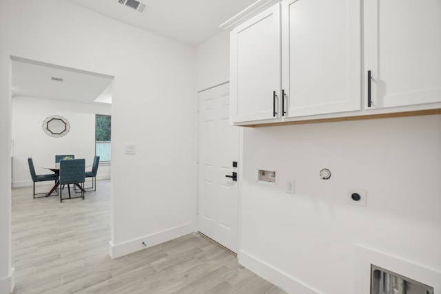 laundry area with cabinets, hookup for a washing machine, hookup for an electric dryer, gas dryer hookup, and light hardwood / wood-style flooring