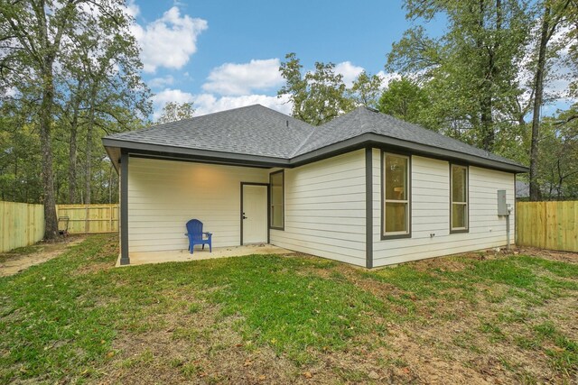 back of house with a fenced backyard, a shingled roof, a patio, and a yard