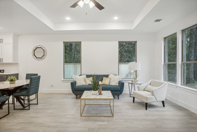 living room with ceiling fan, light hardwood / wood-style floors, and a raised ceiling