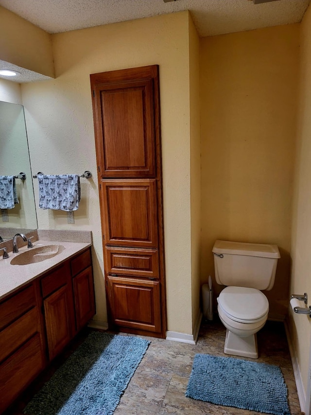 bathroom with vanity, toilet, and a textured ceiling