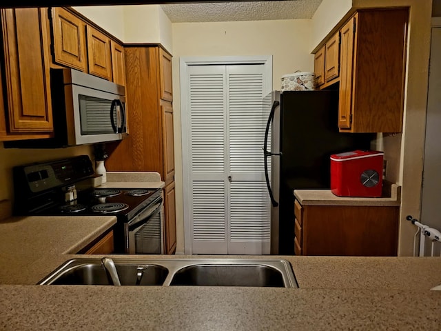 kitchen featuring electric range, black fridge, and a textured ceiling