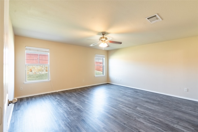 empty room featuring ceiling fan, a healthy amount of sunlight, and dark hardwood / wood-style flooring