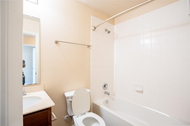 full bathroom featuring tiled shower / bath, vanity, and toilet