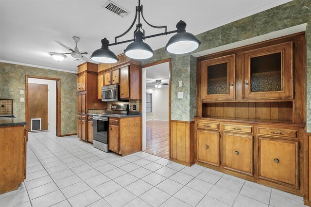 kitchen featuring pendant lighting, light tile patterned flooring, ornamental molding, and appliances with stainless steel finishes