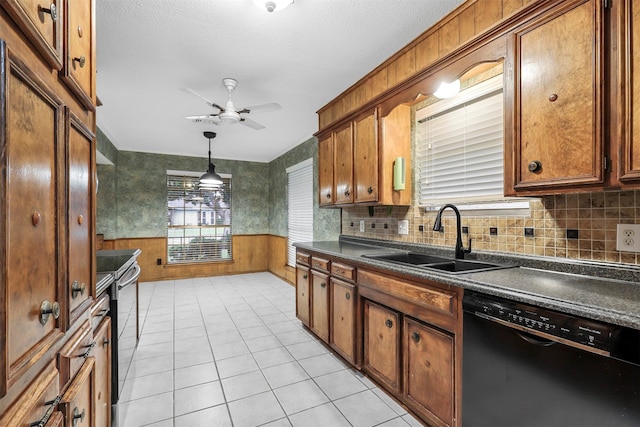 kitchen with dishwasher, sink, wood walls, decorative light fixtures, and light tile patterned floors