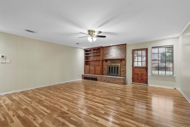 unfurnished living room featuring ceiling fan, light hardwood / wood-style floors, built in features, and a brick fireplace