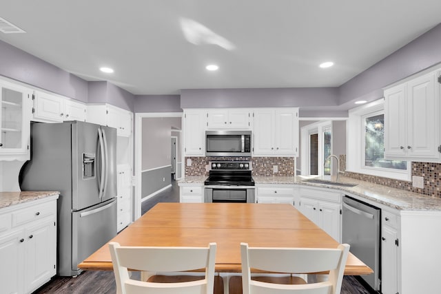 kitchen with sink, tasteful backsplash, dark hardwood / wood-style flooring, white cabinetry, and stainless steel appliances