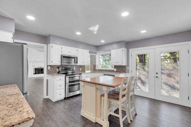 kitchen with white cabinets, stainless steel appliances, a kitchen island, and dark hardwood / wood-style floors