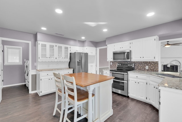 kitchen featuring stainless steel appliances, dark wood-type flooring, sink, separate washer and dryer, and white cabinets