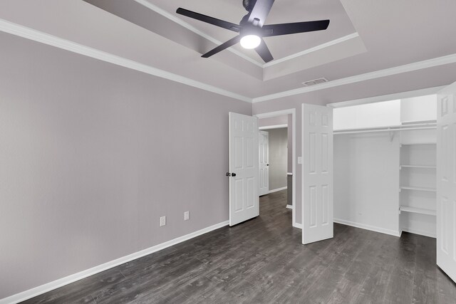 unfurnished bedroom with a raised ceiling, ceiling fan, dark wood-type flooring, and ornamental molding