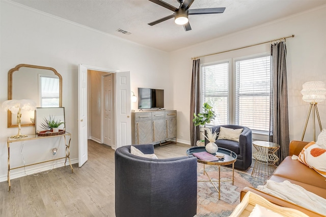 living room featuring ornamental molding, ceiling fan, and light wood-type flooring