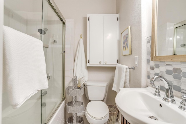 full bathroom with sink, shower / bath combination with glass door, and toilet