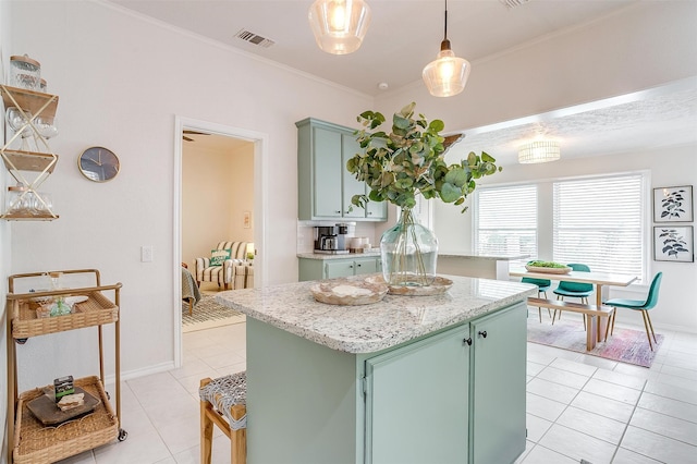 kitchen featuring a center island, light tile patterned floors, ornamental molding, green cabinets, and pendant lighting