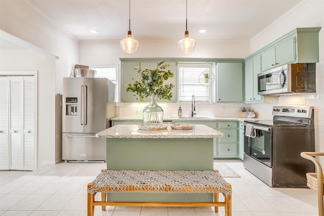 kitchen featuring sink, light stone counters, tasteful backsplash, a center island, and appliances with stainless steel finishes