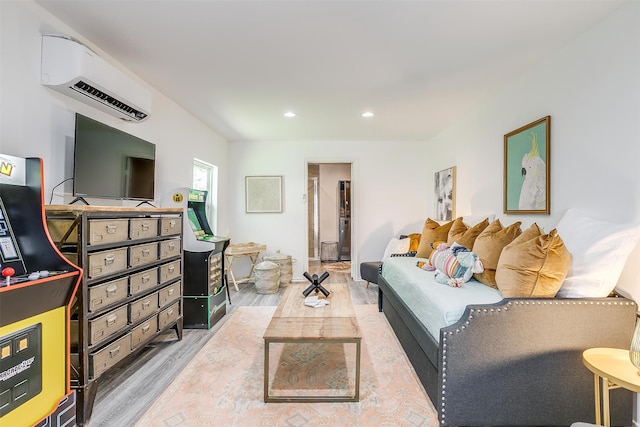 living room with an AC wall unit and light hardwood / wood-style flooring