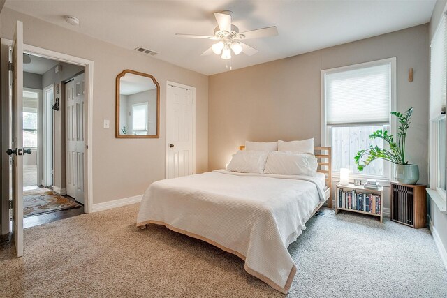 carpeted bedroom featuring multiple windows and ceiling fan