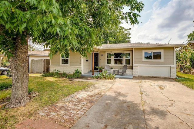 ranch-style house with a front lawn, covered porch, and a garage