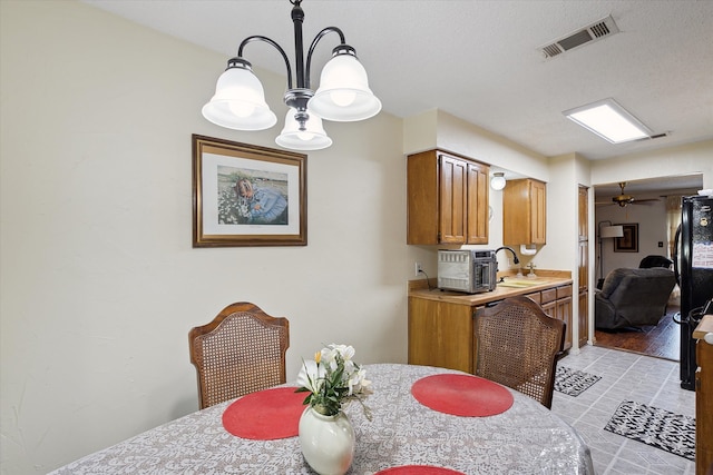 dining room featuring a textured ceiling, ceiling fan with notable chandelier, sink, and light hardwood / wood-style flooring