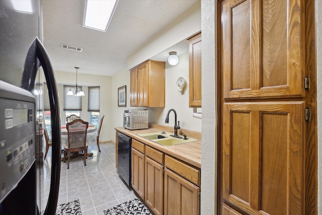 kitchen featuring sink, a textured ceiling, black dishwasher, decorative light fixtures, and a chandelier