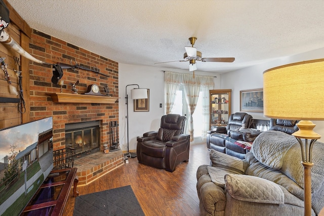 living room with hardwood / wood-style floors, a fireplace, ceiling fan, and a textured ceiling