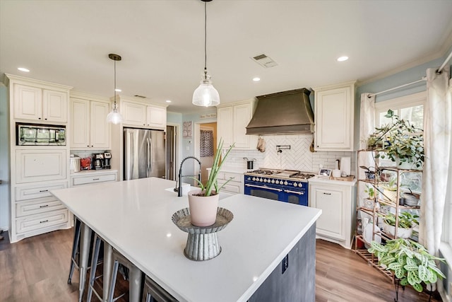 2225 W Park Ave, Corsicana, TX 75110 - kitchen with appliances with stainless steel finishes, custom exhaust hood, backsplash, a center island with sink, and light countertops