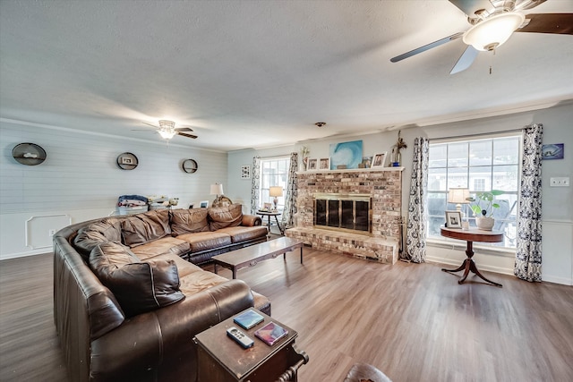 living room featuring a wealth of natural light, a fireplace, ornamental molding, and hardwood / wood-style flooring