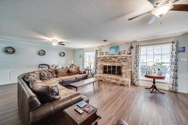 2225 W Park Ave, Corsicana, TX 75110 - living room with a ceiling fan, wood finished floors, a brick fireplace, baseboards, and a textured ceiling