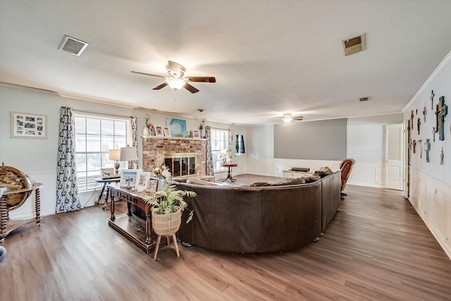 living room featuring a fireplace, wood-type flooring, plenty of natural light, and ornamental molding