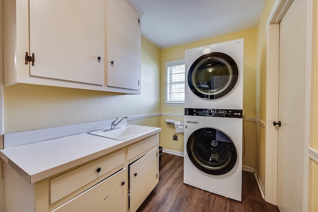 laundry area with sink, dark wood-type flooring, cabinets, crown molding, and stacked washer / drying machine