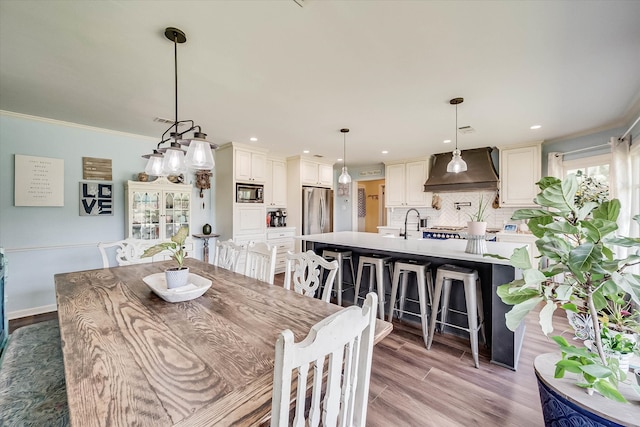 dining room with crown molding, light hardwood / wood-style flooring, and sink